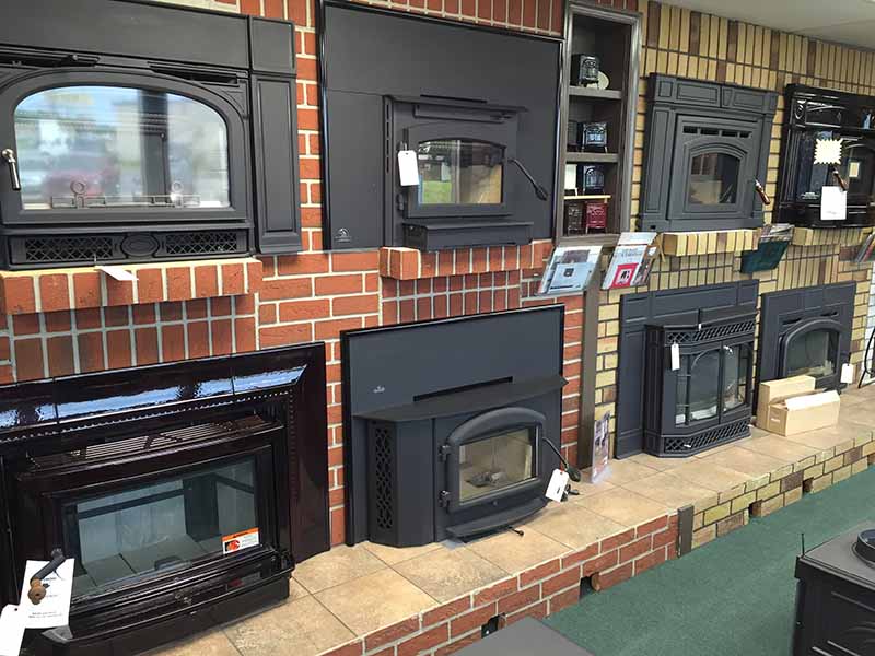 Various shapes and sizes of fireplaces on Wall for display inside Ace Stove Store.  We service and sell woodburning, pellet, electric and gas stoves.